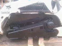 A bobcat track loader is sitting on top of a concrete block.