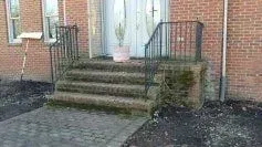 There are stairs leading up to the front door of a brick building.