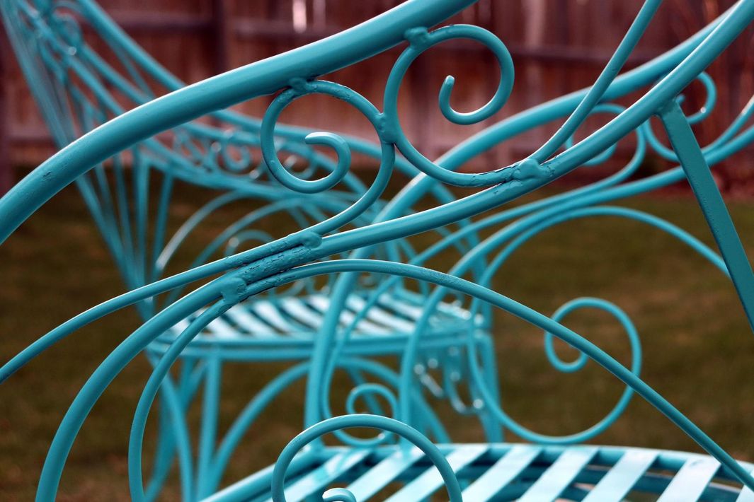 A close up of a blue and white wrought iron bench.