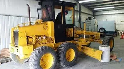 A yellow tractor is parked in a garage.