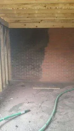 A hose is sitting in a room next to a brick wall.