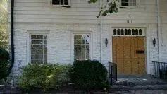 A white brick house with a wooden garage door and windows.