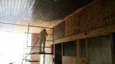 A man is standing on a scaffolding painting the ceiling of a building.