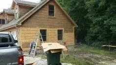 A truck is parked in front of a wooden house under construction.