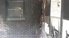 A brick wall with a window and a chair in it.
