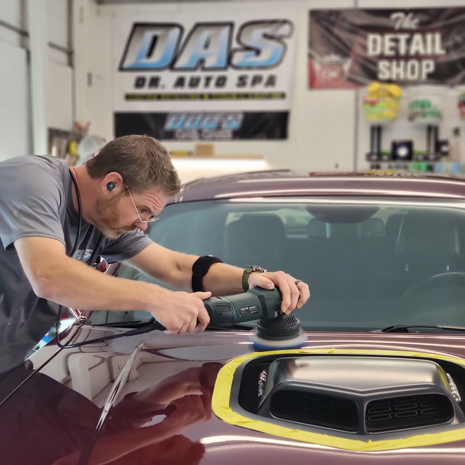 A man is polishing the hood of a car at Dr Auto Spa detailing shop.