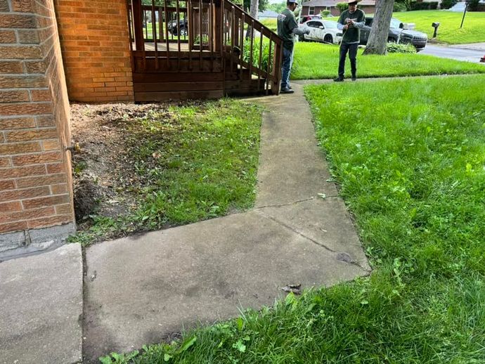A couple of people standing on a sidewalk in front of a house.
