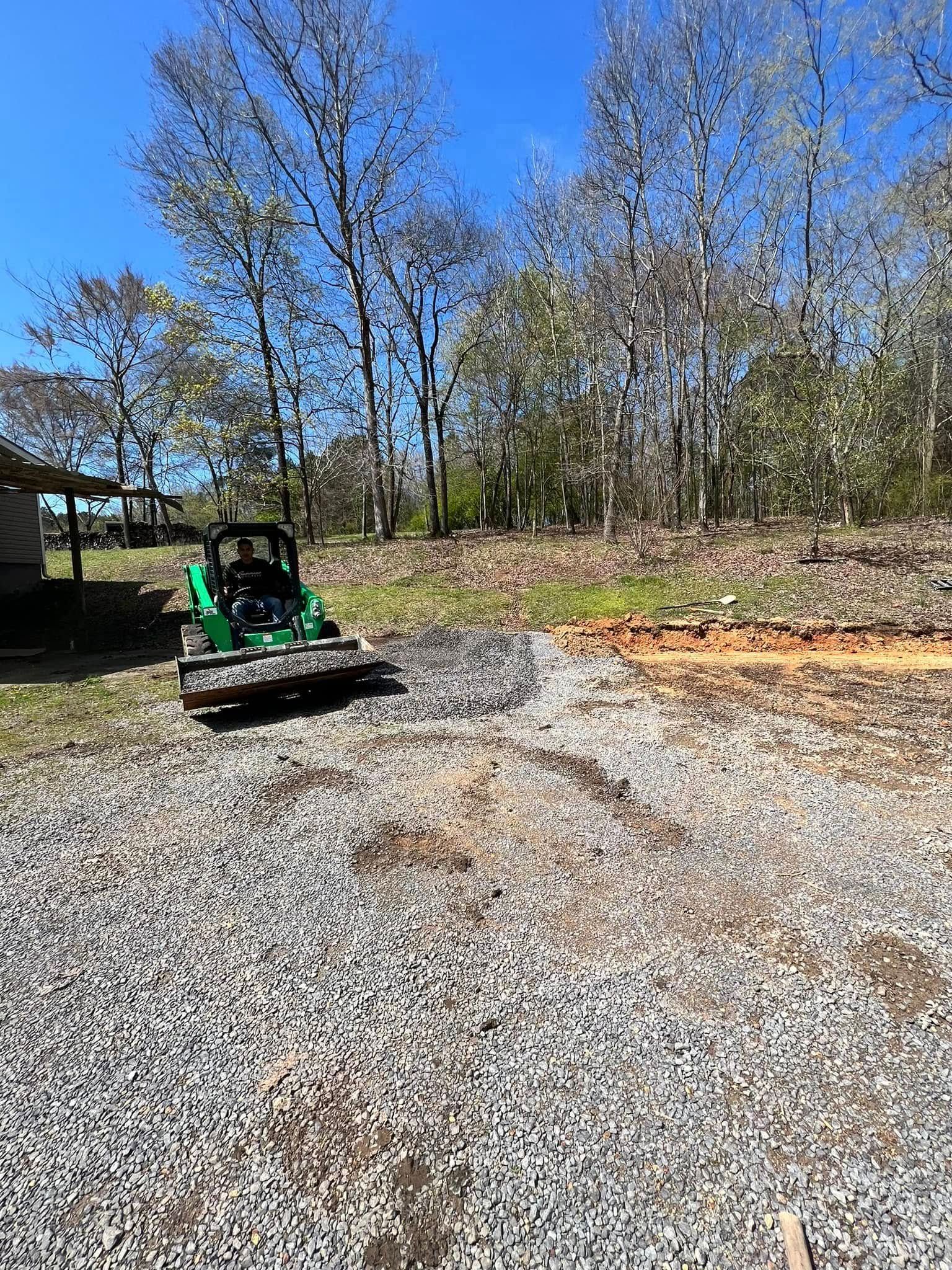 A green tractor is parked in a gravel lot.