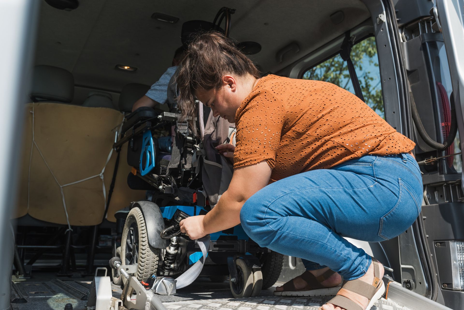 A woman is fixing a wheelchair in the back of a van.