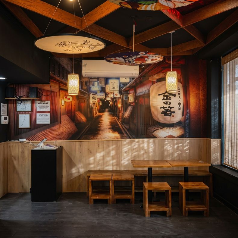 Cozy Japanese-style restaurant interior with wooden tables, lanterns, and a mural wall