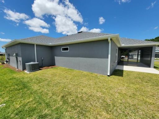 Gray house with white trim, green lawn, and blue sky.