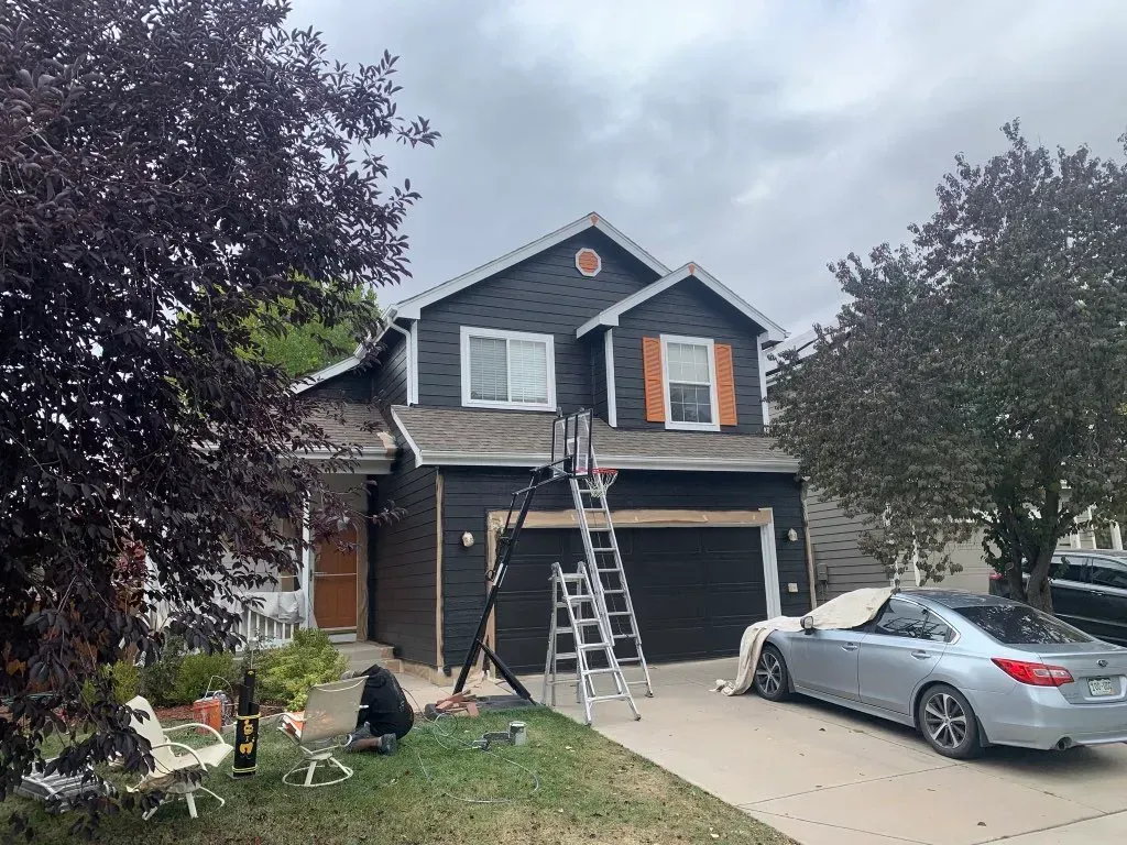 A car is parked in front of a house that is being painted.