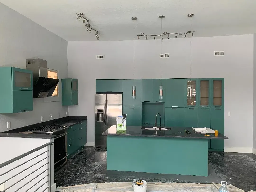 A kitchen with green cabinets and a large island in the middle.