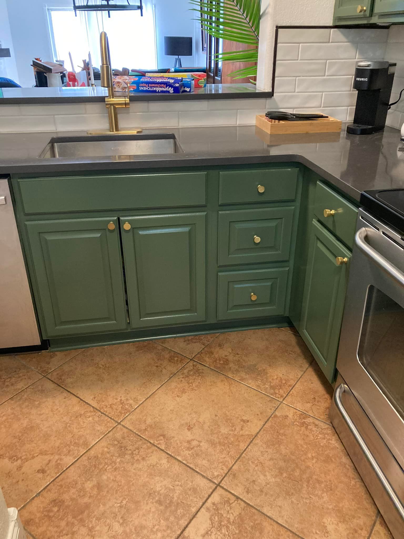 A kitchen with green cabinets , a sink , and a stove.