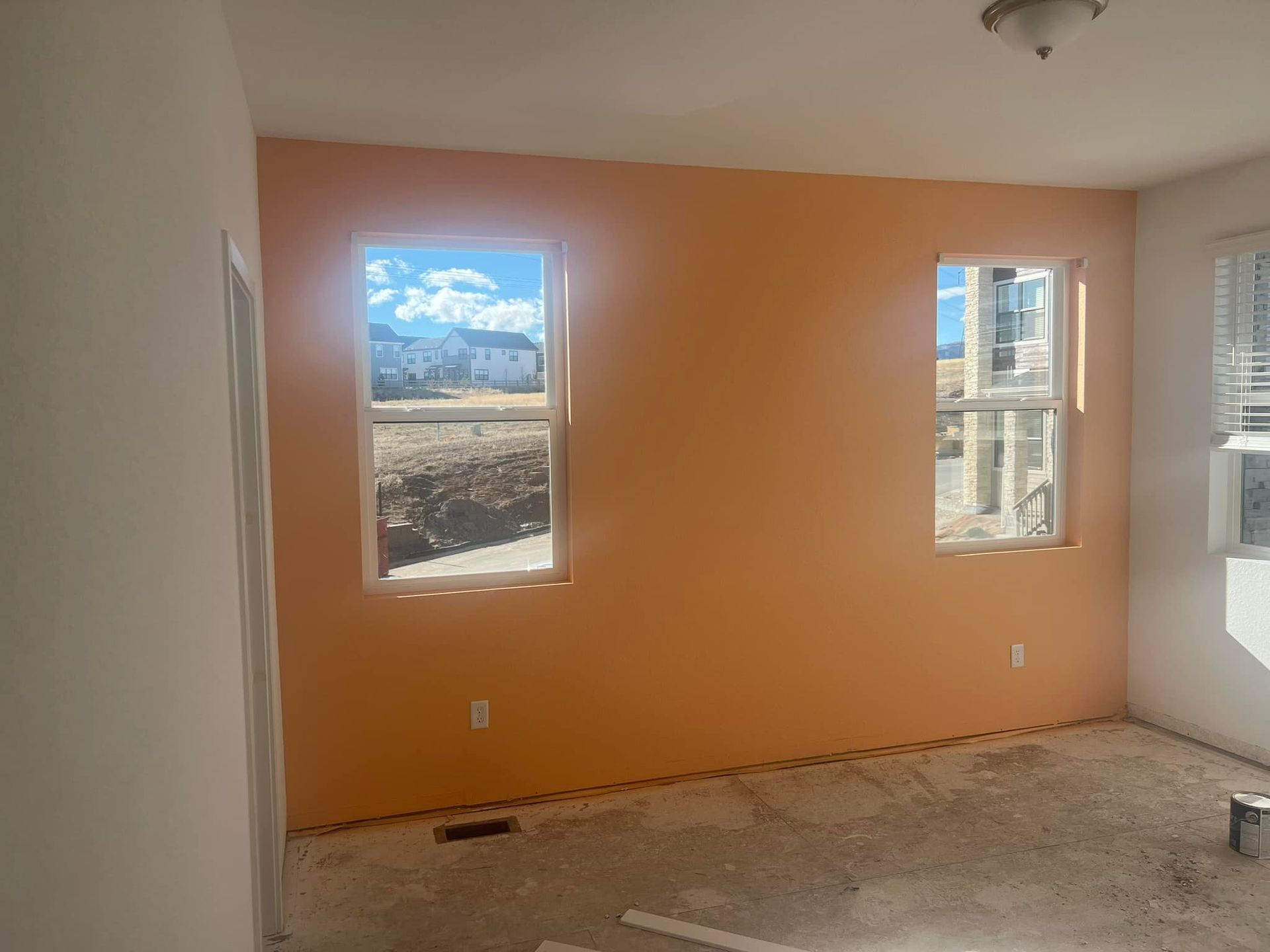 An empty room with orange walls and two windows