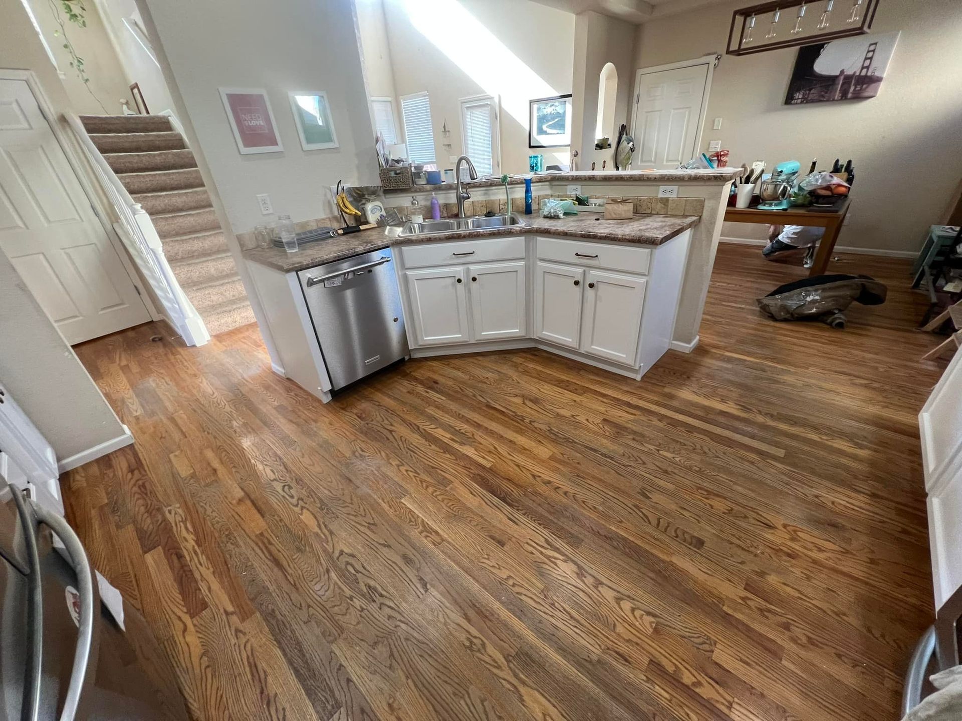 A kitchen with hardwood floors and white cabinets and a sink.
