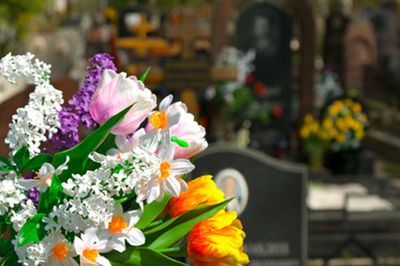 A bouquet of flowers is sitting in front of a grave in a cemetery.