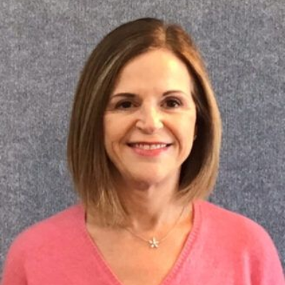 Portrait of a smiling woman in a pink sweater against a gray background