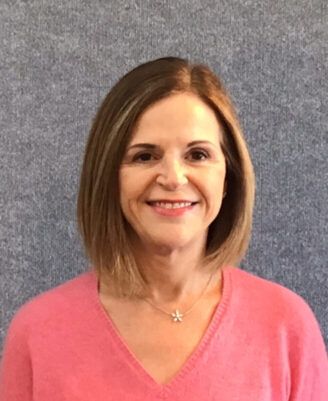 Portrait of a smiling woman in a pink sweater against a gray background