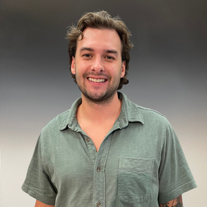 Smiling man in a light green shirt against a gray background
