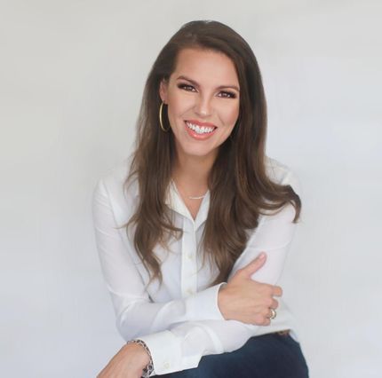 Smiling woman in a white blouse with folded arms against a light background