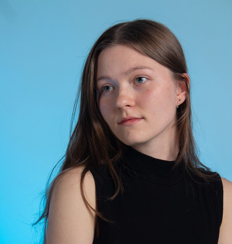 Portrait of a woman in a black sleeveless top against a blue background