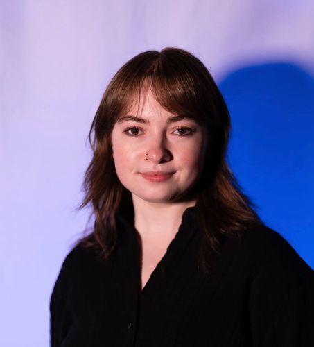 Portrait of a woman in a black top against a purple and blue studio background