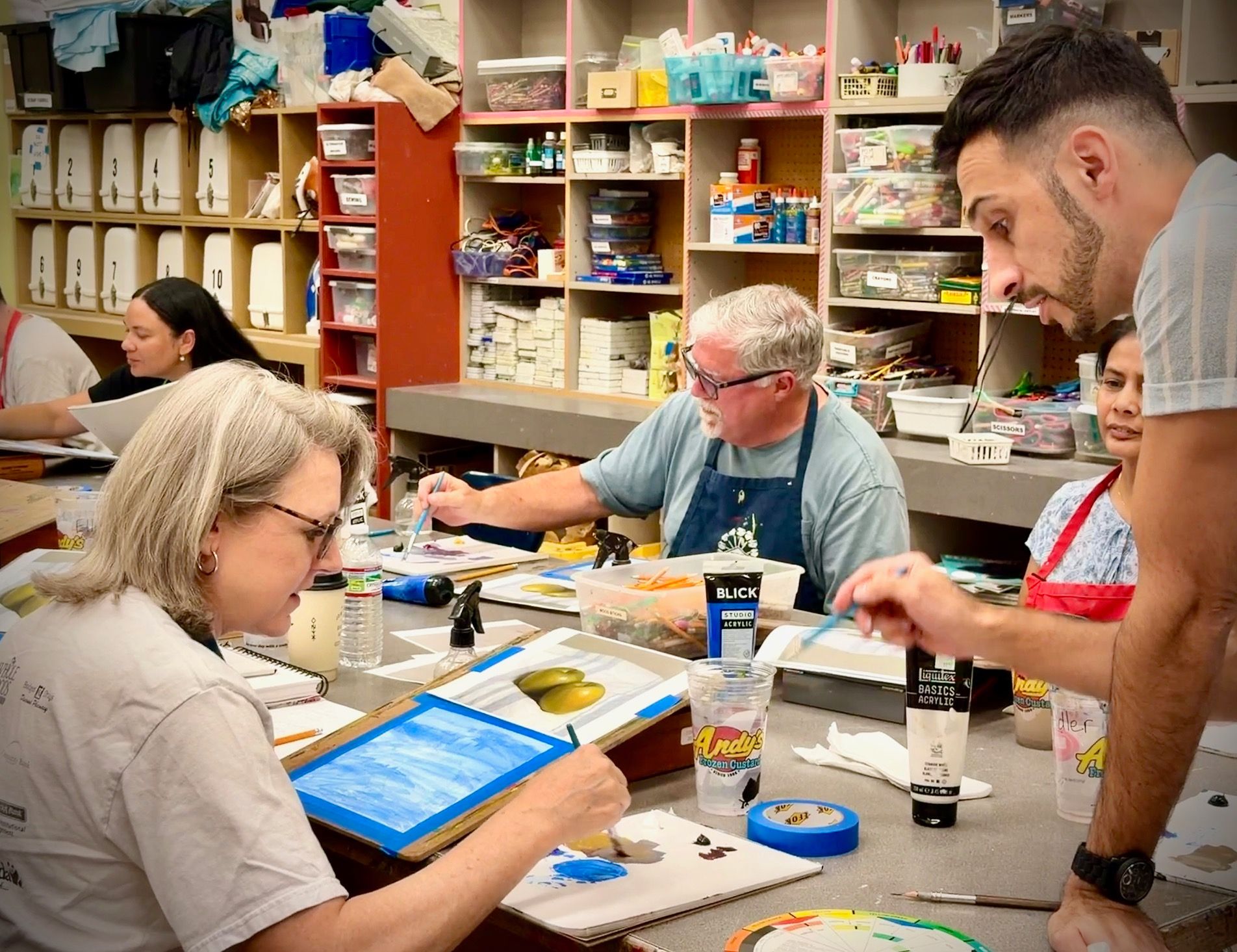People painting with black-and-white reference photos at a craft table