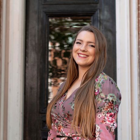 Smiling woman in a floral dress standing in a doorway