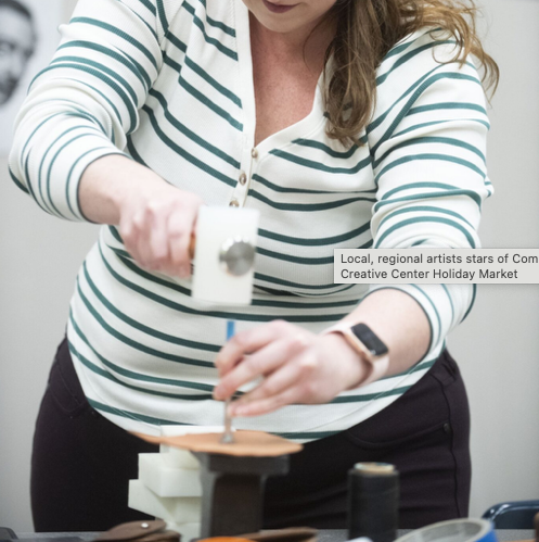 Woman in striped top using a mallet and stamp in leather making class.