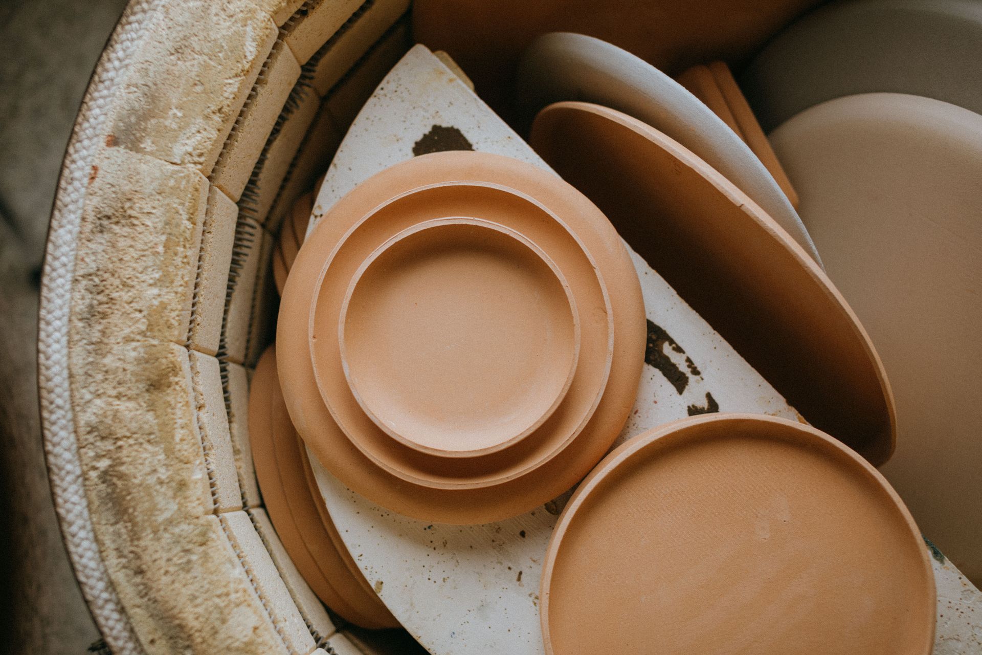 Assorted beige ceramic plates and bowls stacked in a kiln