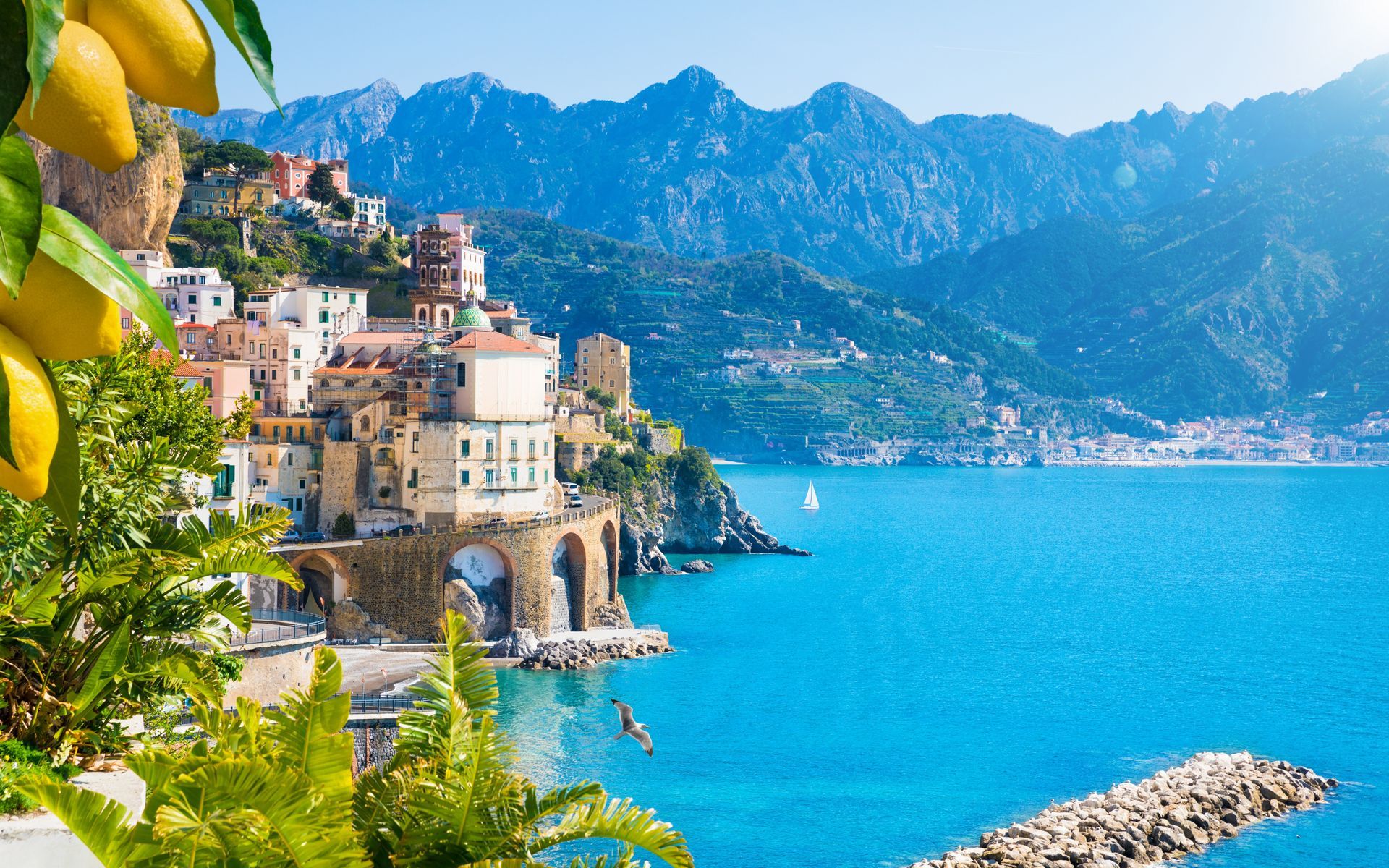 A city on a hill overlooking a body of water with mountains in the background.