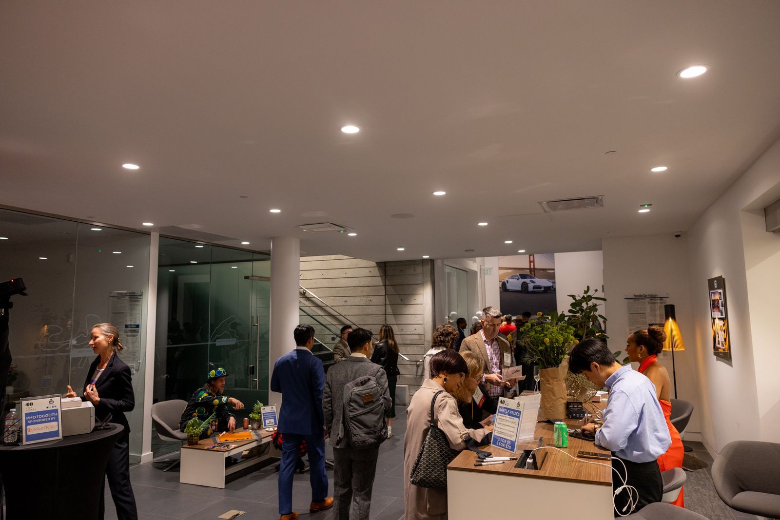 People gathered in a modern office lobby around a reception desk with plants and wall-mounted screens.