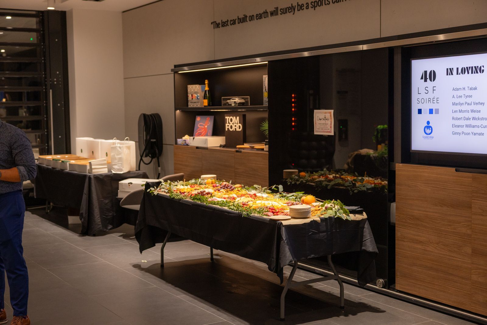 Buffet table with snacks and drinks in a conference room, next to a wall display and shelves.