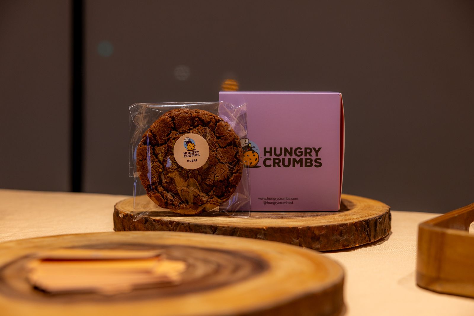 Hungry Crumbs cookie packaging on a wooden display stand with a biscuit in front