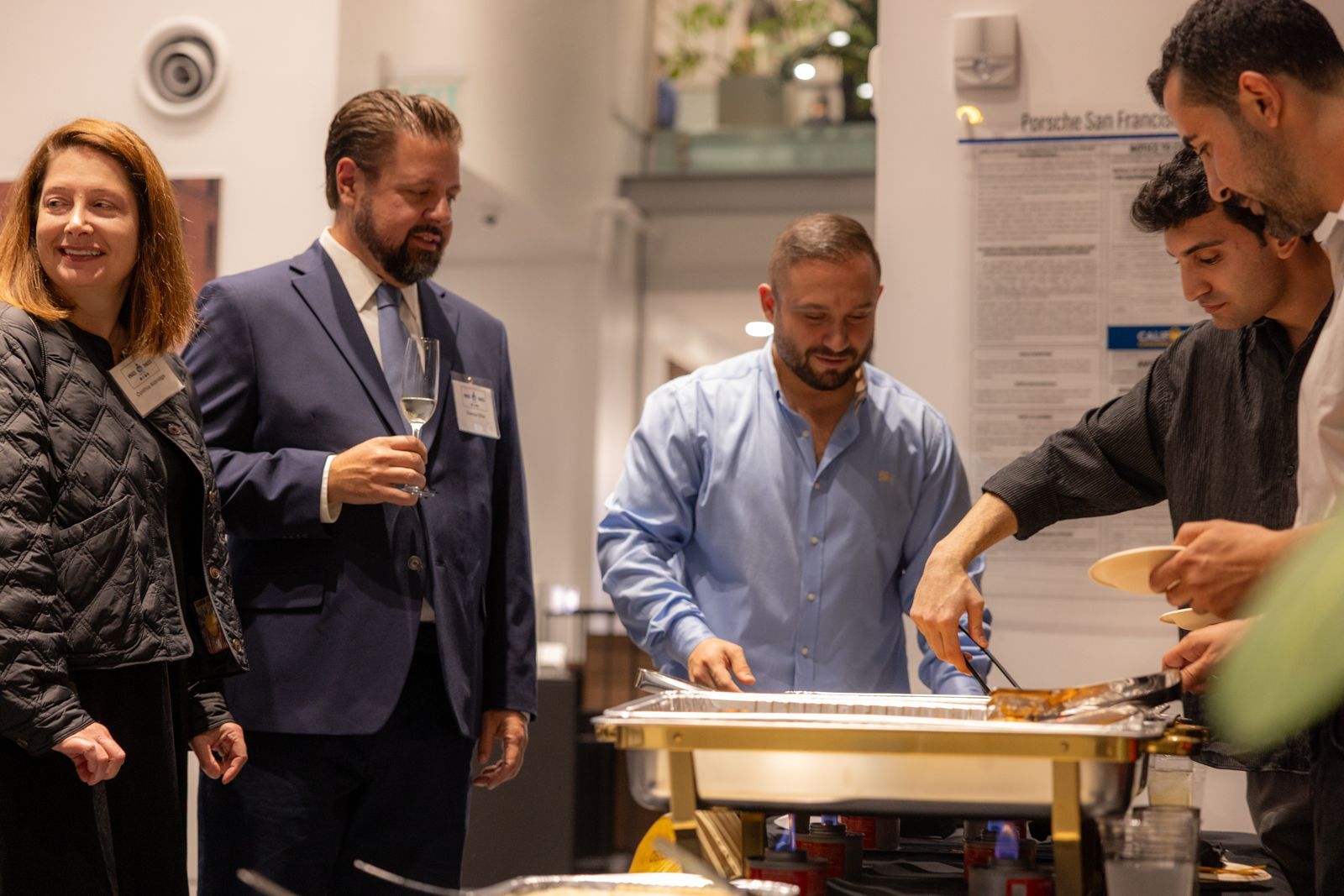 People serving food at a buffet table in a bright indoor event space