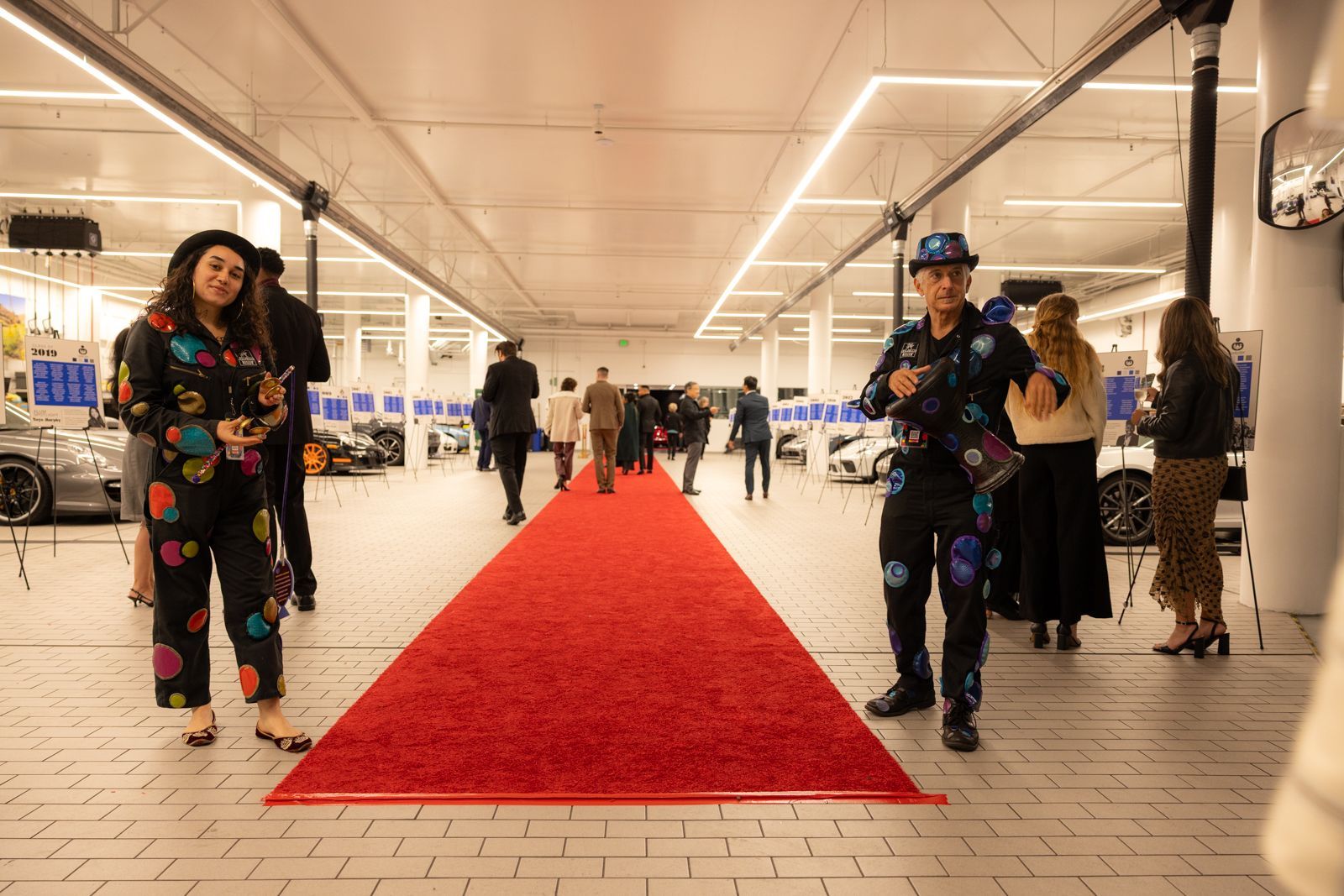 Red carpet runway in a bright indoor hall with people walking on both sides.