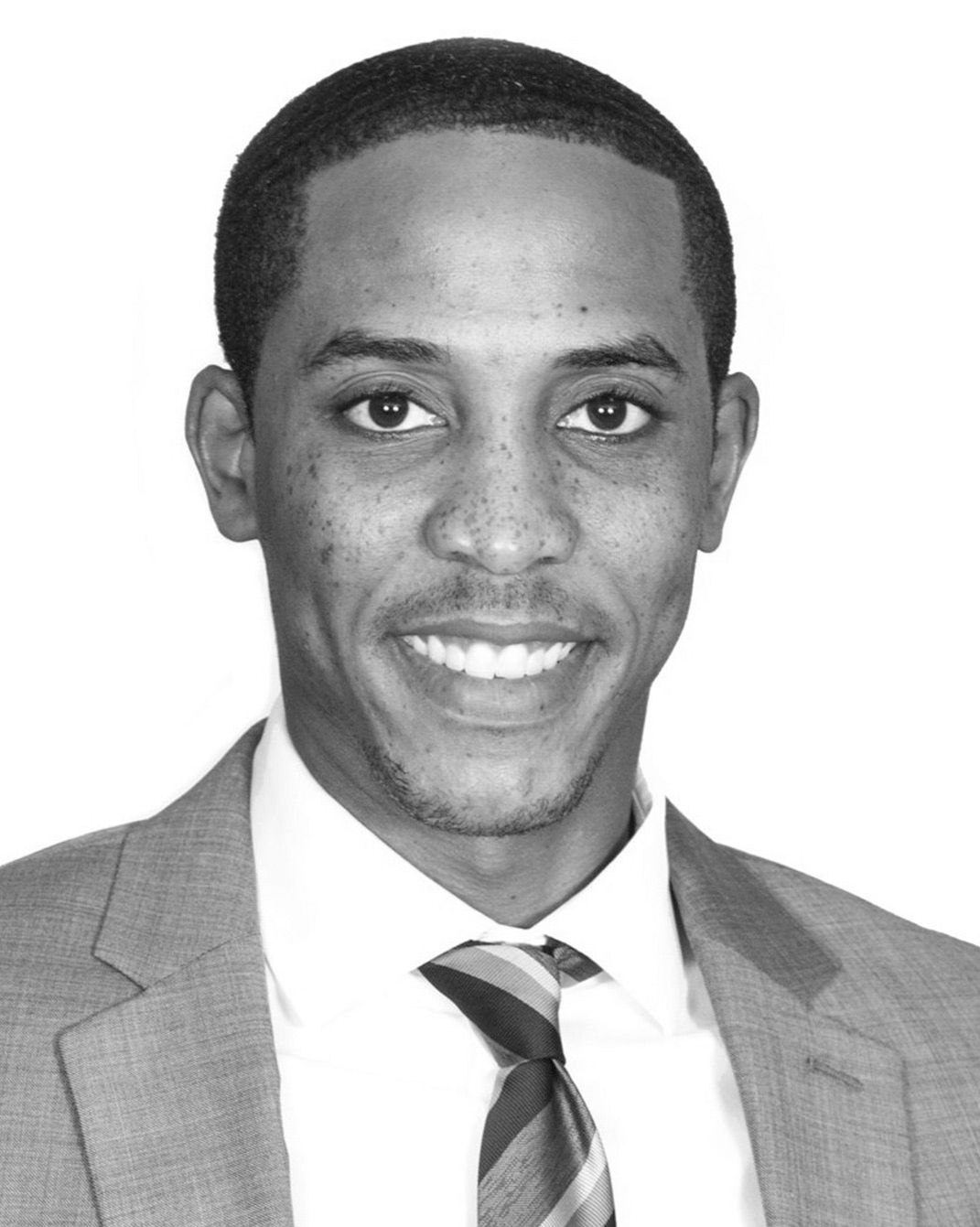 Smiling man in a suit and striped tie against a plain background
