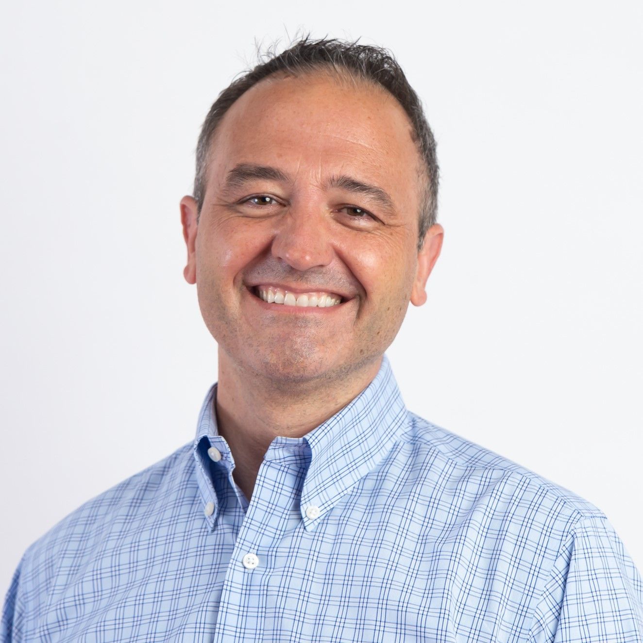 Smiling man in a light blue button-up shirt against a white background