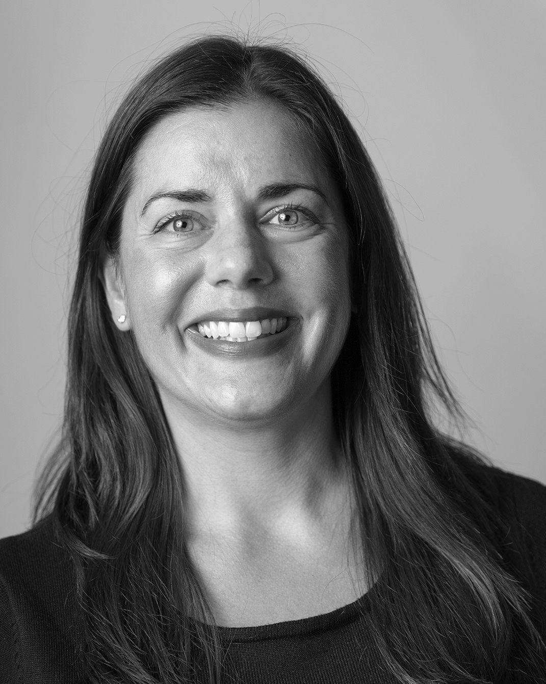 Smiling woman with long dark hair against a plain gray background