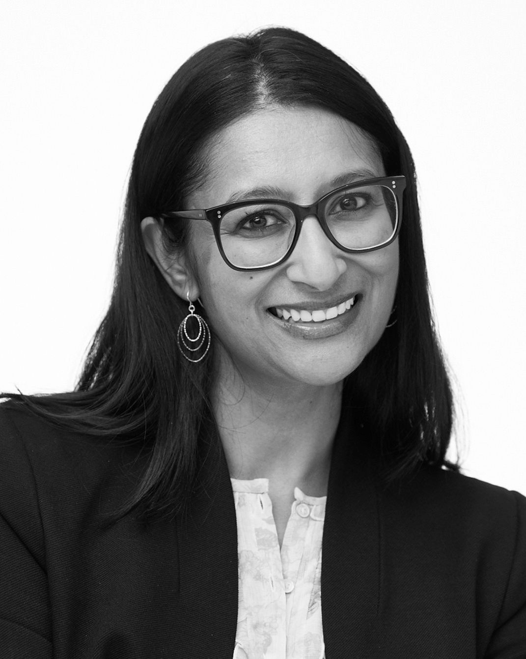 Portrait of a smiling woman with glasses in a dark blazer on a white background