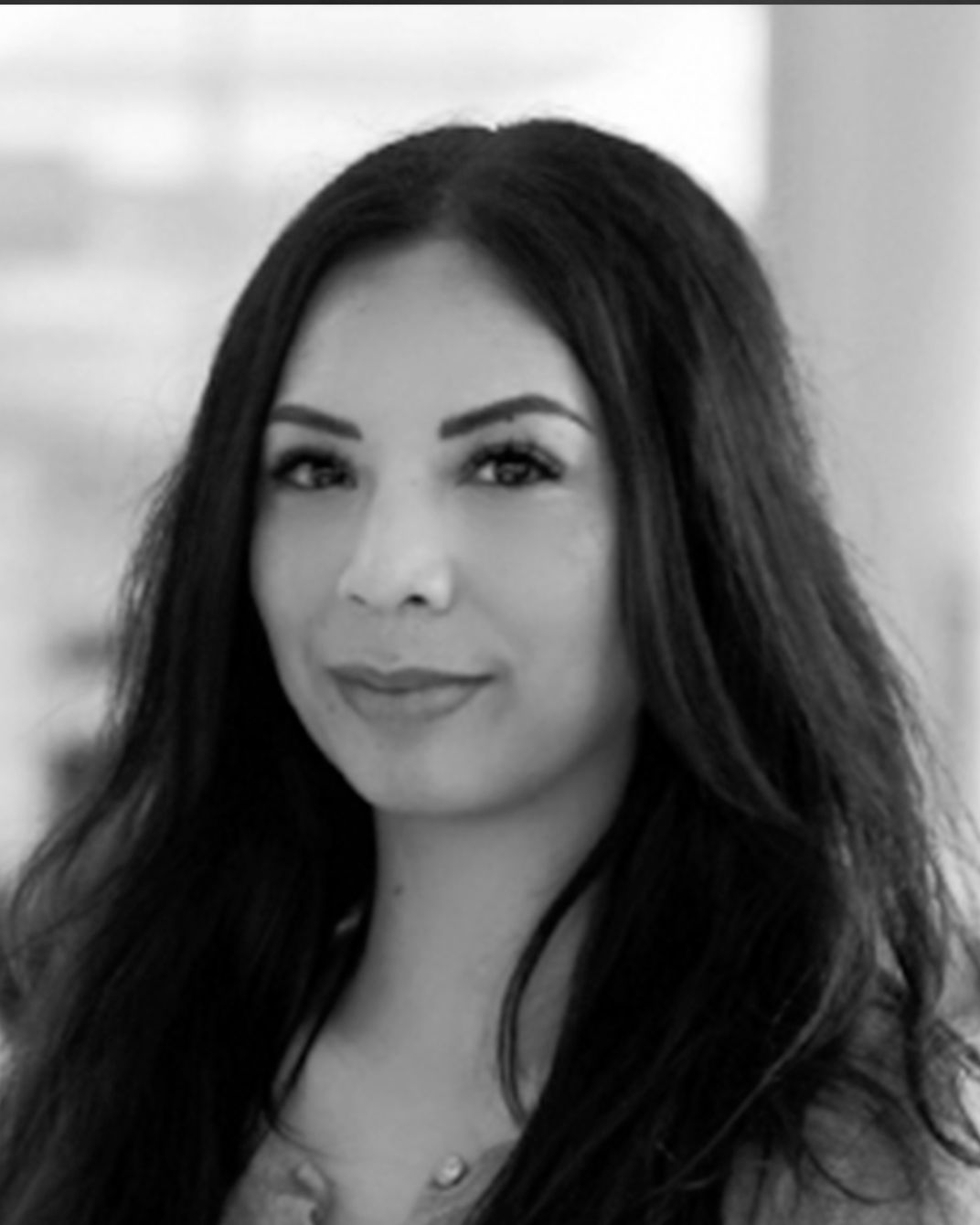 Black-and-white portrait of a woman with long dark hair, facing forward with a slight smile.