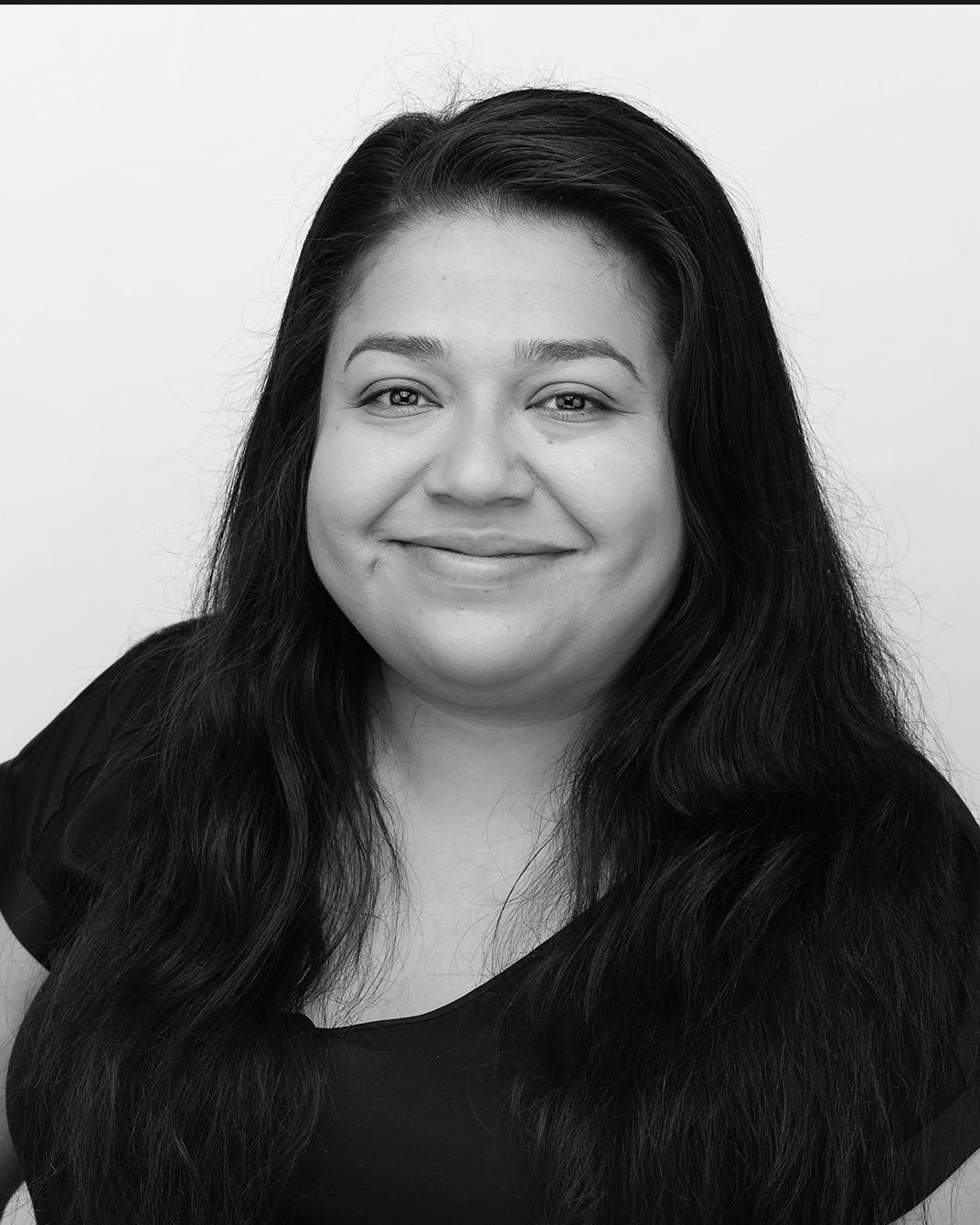 Portrait of a smiling woman with long dark hair against a plain light background