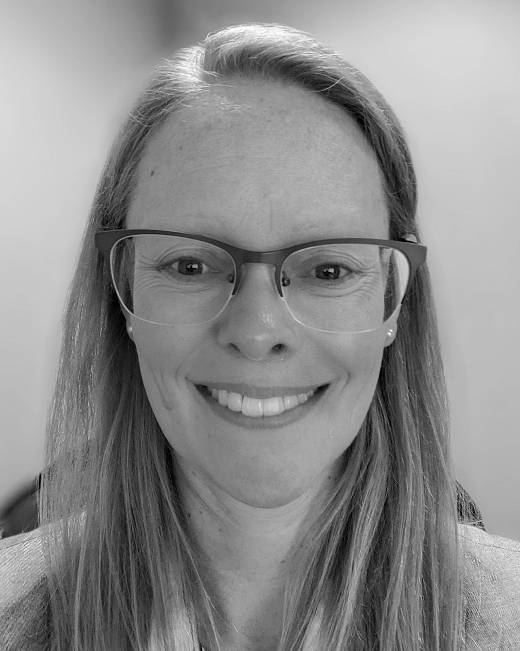 Smiling person wearing glasses in a black-and-white close-up portrait