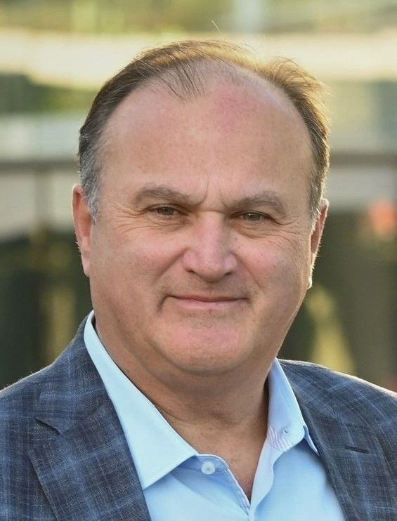 Portrait of a smiling man in a blue blazer and light blue shirt outdoors