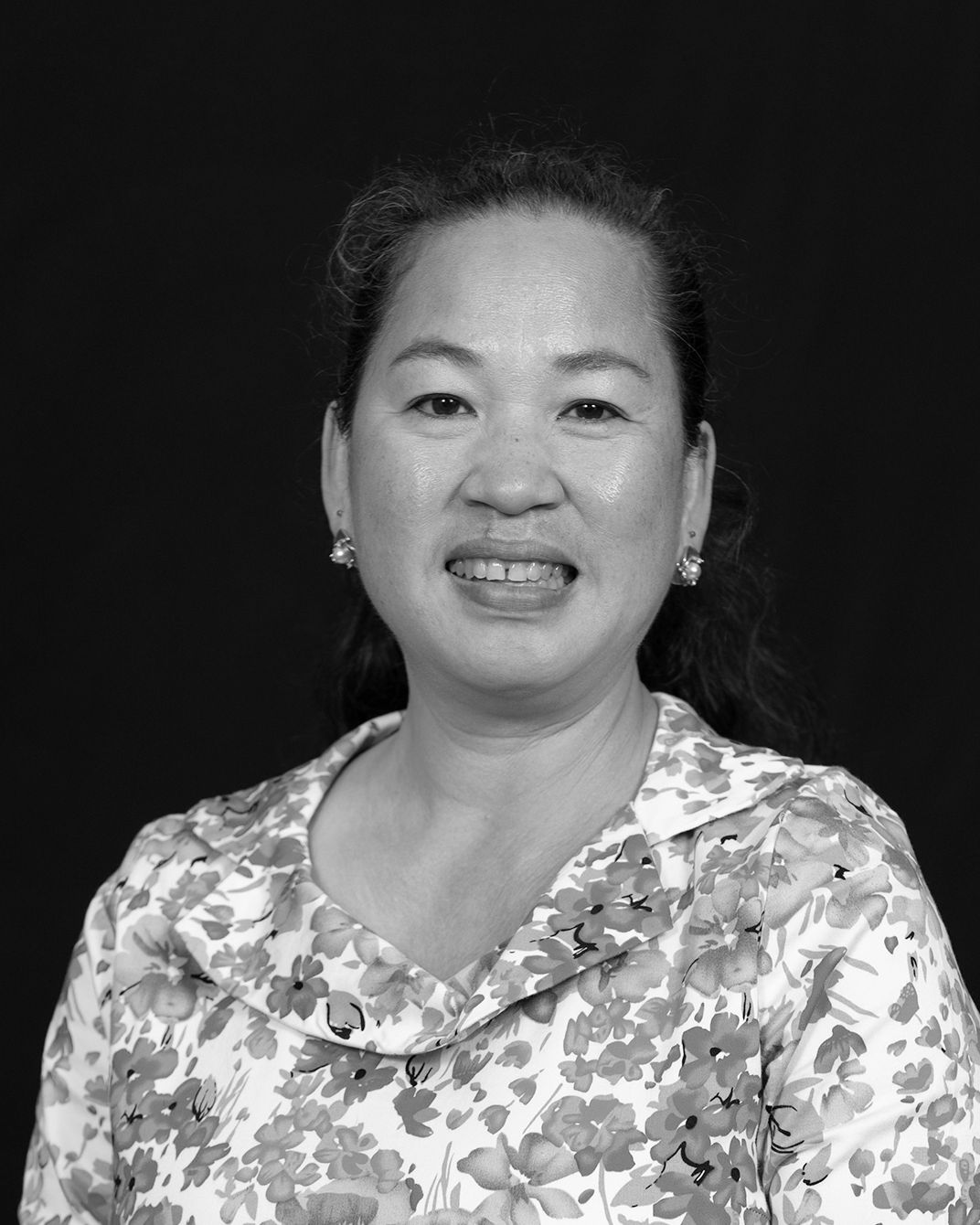 Smiling woman in a floral blouse against a dark background