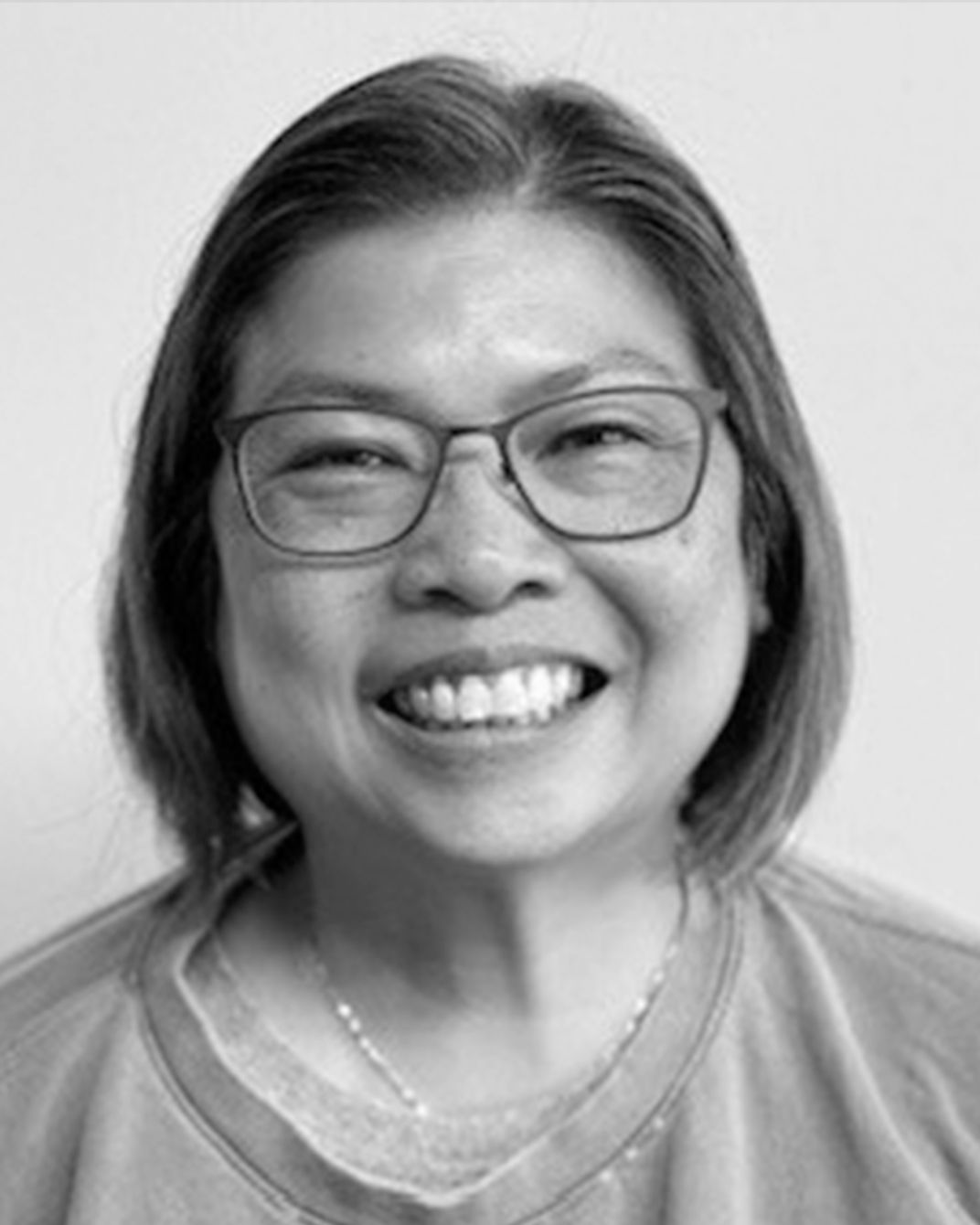 Smiling person wearing glasses in a black-and-white portrait