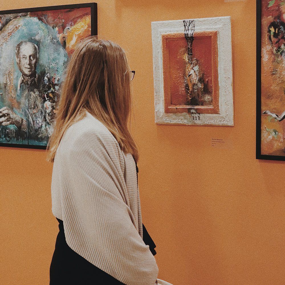 Person viewing framed artwork in a gallery with orange walls