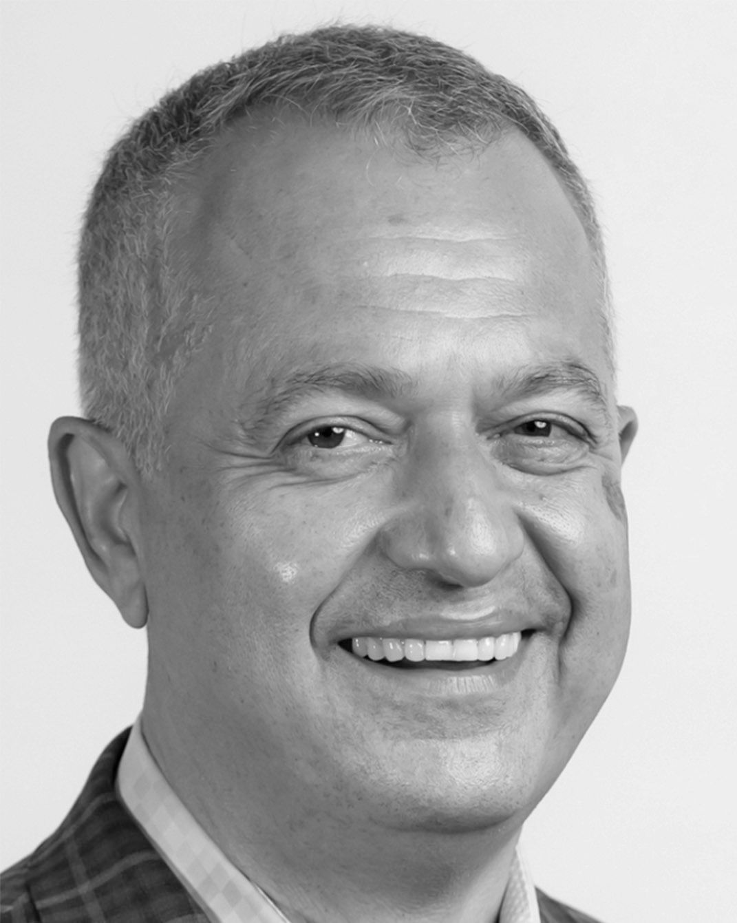 Smiling man in a plaid shirt, shown in a black-and-white headshot.