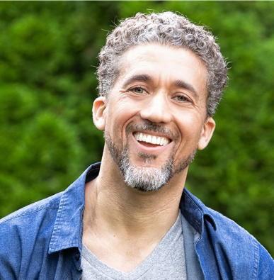 Smiling person outdoors in a blue shirt against a green blurred background